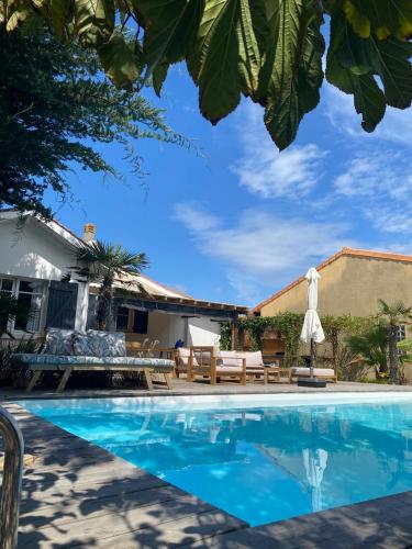 une piscine avec des chaises et une table ainsi qu'une maison dans l'établissement Cozy house next to the sea, à Lacanau