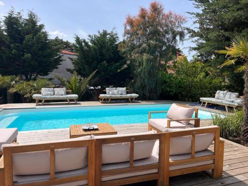 une cour avec une piscine, des chaises et une table dans l'établissement Cozy house next to the sea, à Lacanau