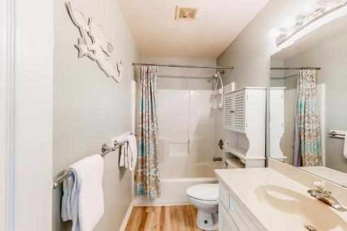 a white bathroom with a toilet and a sink at Blue Crab Bungalow in Padre Island
