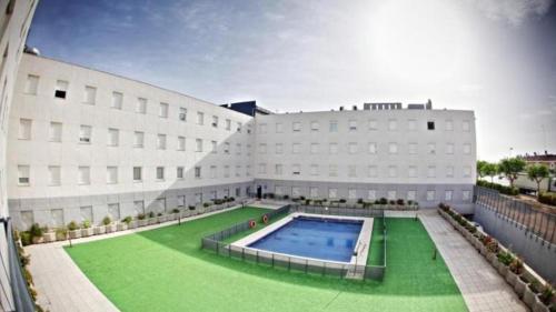 a large building with a swimming pool in front of it at ApartHome® in Bormujos
