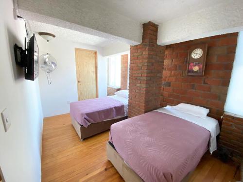 sypialnia z 2 łóżkami i ceglaną ścianą w obiekcie Hotel RJ Querétaro w mieście Querétaro