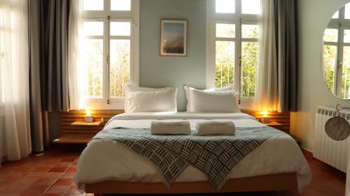 a bedroom with a large bed with two windows at Breathe Hotel in Batroûn