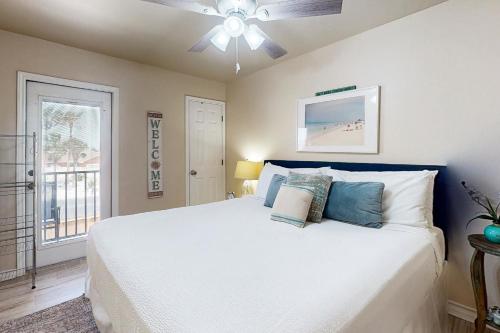 1 dormitorio con 1 cama blanca y ventilador de techo en Feelin' Beachy, en Padre Island