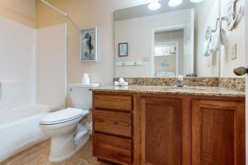 bagno con servizi igienici, lavandino e specchio di Feelin' Beachy a Padre Island