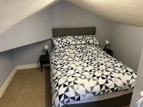 a bedroom with a bed with a black and white comforter at Bold Street House in Warrington