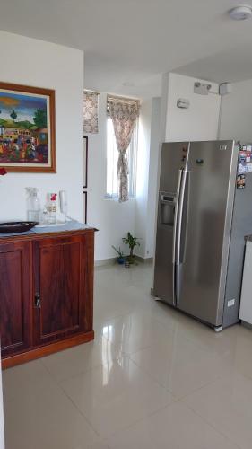 una cocina con nevera de acero inoxidable y armarios de madera en Apartamento de Yuly, en Santa Marta