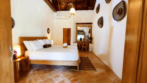 蒙波斯HOTEL NIETO MOMPOX, ubicado en el corazón del centro histórico, frente al rio magdalena en zona de malecón的卧室里有一张白色的床和一面镜子