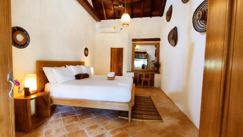 a bedroom with a white bed and a mirror at HOTEL NIETO MOMPOX, ubicado en el corazón del centro histórico, frente al rio magdalena en zona de malecón in Mompos