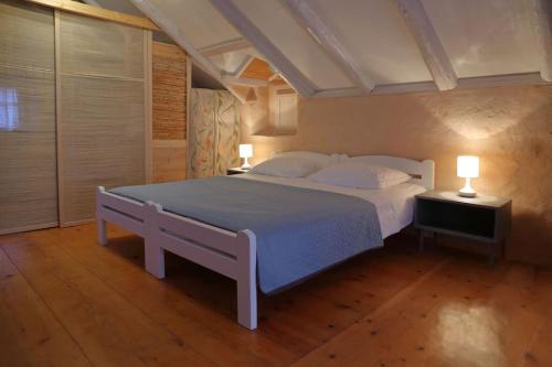 a bedroom with a large white bed with two lamps at Stonehome Pojata in Rušići