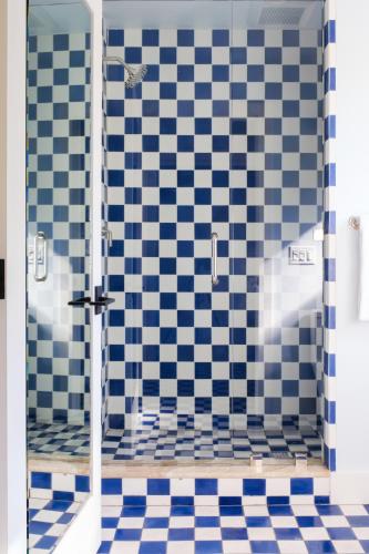 a bathroom with a shower with blue and white tiles at River Lodge Paso - 21 & Over Pool in Paso Robles