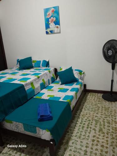 a bedroom with two beds and a fan at Apartamento El Remanso in Palmira