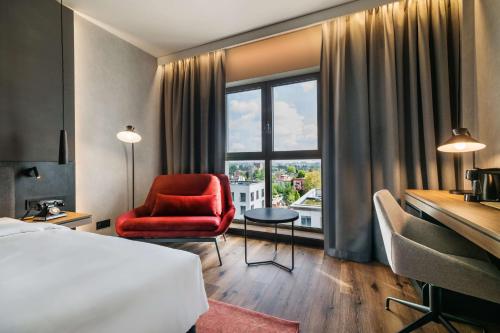 una camera d'albergo con un letto, una sedia e una finestra di Radisson RED Hotel & Radisson RED Apartments, Kraków a Cracovia