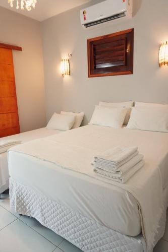 a bedroom with two beds with white sheets and towels at Pousada Camocim Beach in Camocim