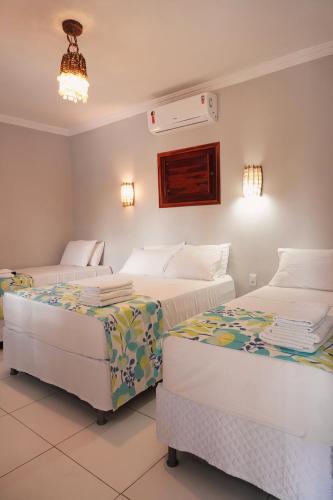 a bedroom with two beds and a chandelier at Pousada Grand Fortim in Camocim