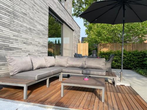 a couch and a table and an umbrella on a deck at Tranquilo Maaseik in Maaseik