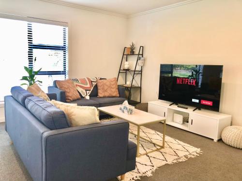 a living room with a blue couch and a tv at Fashion,Bright and Spacious,Superior location in Hamilton
