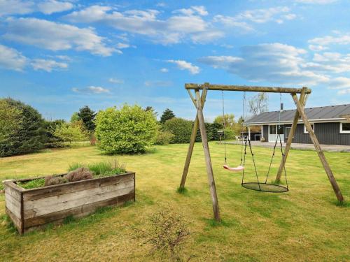 a swing in a yard next to a field at 7 person holiday home in Fjerritslev-By Traum in Fjerritslev