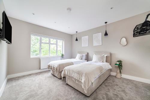 2 bedden in een slaapkamer met witte muren en een raam bij Arte Stays - New & Spacious 2 Bedroom Flat - close by Wembley Stadium - Parking in Londen