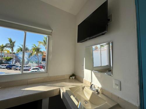 a bathroom with a sink and a mirror and a window at Isla Venados Habitaciones Vacacionales in Mazatlán