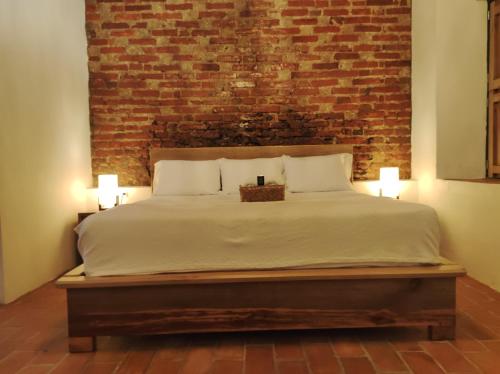 a bedroom with a large bed with a brick wall at HOTEL NIETO MOMPOX, ubicado en el corazón del centro histórico, frente al rio magdalena en zona de malecón in Mompos