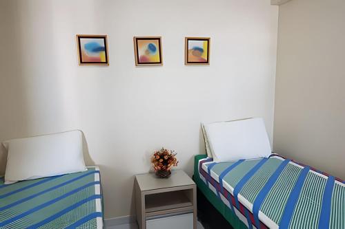 two beds in a room with a table and pictures on the wall at Apto em Tambaú no coração turístico da cidade ! in João Pessoa