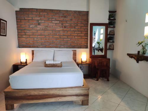 a bedroom with a white bed and a brick wall at HOTEL NIETO MOMPOX, ubicado en el corazón del centro histórico, frente al rio magdalena en zona de malecón in Mompos