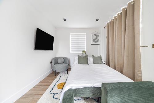 1 dormitorio con 1 cama grande y 1 silla en Arte Stays - Modern and Newly refurbished Penthouse - Heart of Wembley - w private parking, en Londres