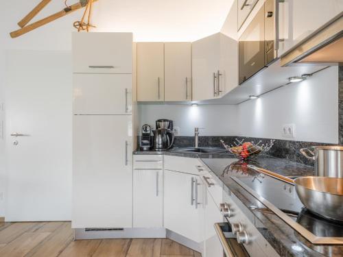 a kitchen with white cabinets and stainless steel appliances at BergbiberLODGE S in Piesendorf