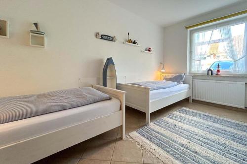 1 dormitorio con 2 camas, ventana y alfombra en Ferienwohnung-9-mit-Terrasse-Garten-Landhaus-Hubertus-Duhnen, en Cuxhaven