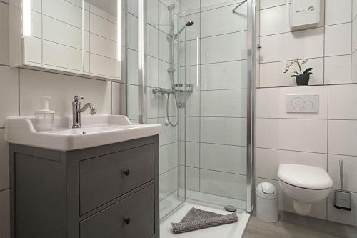 uma casa de banho com um chuveiro, um lavatório e um WC. em Ferienwohnung-9-mit-Terrasse-Garten-Landhaus-Hubertus-Duhnen em Cuxhaven