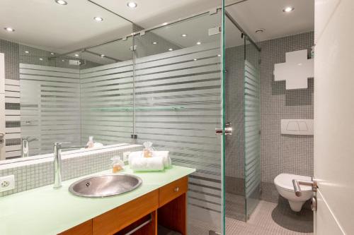 une salle de bain avec un lavabo et une douche en verre dans l'établissement MOANA KEYWEEK Sea view apartment Biarritz downtown, à Biarritz
