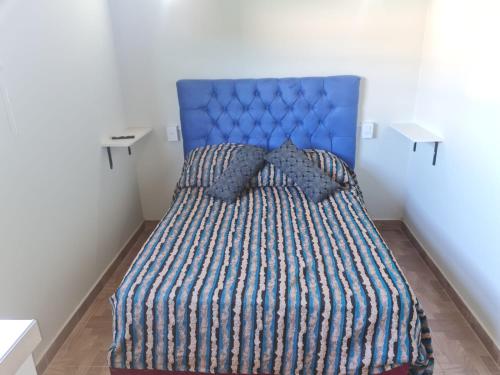 Bett mit blauem Kopfteil in einem Zimmer in der Unterkunft Cabañas La Estrella in Salta
