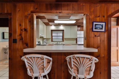 Una cocina con dos sillas en un mostrador en una casa. en 2-2 Beachside Home With Private Pool, en New Smyrna Beach