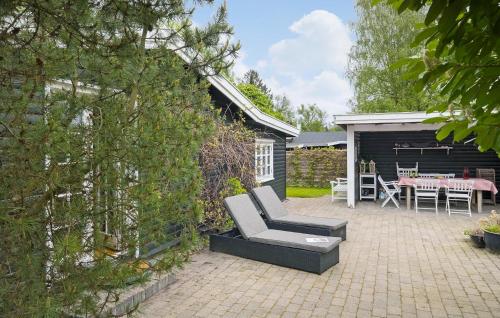 a patio with a chair and a table in a yard at Three-Bedroom Holiday Home In Hornbak in Hornbæk