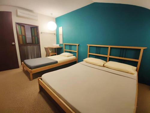 1 dormitorio con 2 camas y pared azul en The Cottage Stay formerly Sunset Homestay 2, en Kuching