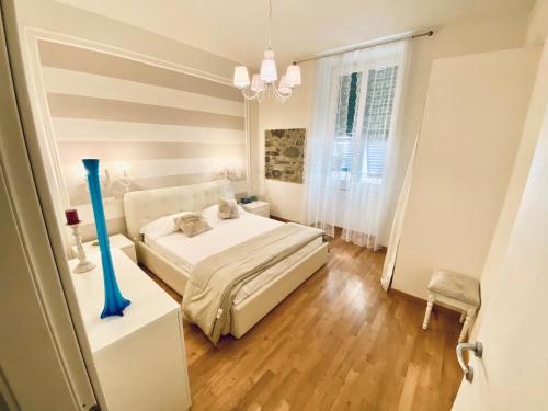 ein Schlafzimmer mit einem weißen Bett und einer blauen Vase in der Unterkunft LEO'S HOME in La Spezia