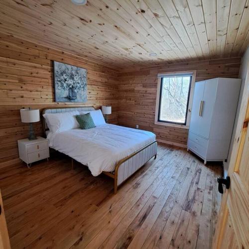 a bedroom with a bed in a wooden cabin at Retreat Lodge - Lochaber Lake Lodges in Antigonish