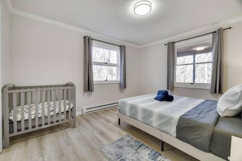 a bedroom with a bed and a crib and two windows at Pocono Mountains Luxury Retreat with king bed & game room in Cresco