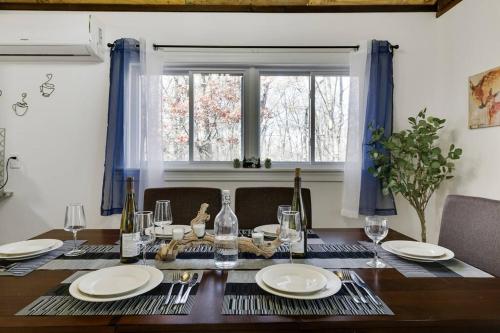 a dining room table with plates and wine glasses at Pocono Mountains Luxury Retreat with king bed & game room in Cresco