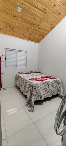 Cama en habitación blanca con techo de madera en Apartamento modelo chalé 201, en Santo Ângelo