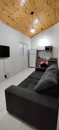 sala de estar con sofá negro y TV en Apartamento modelo chalé 201, en Santo Ângelo
