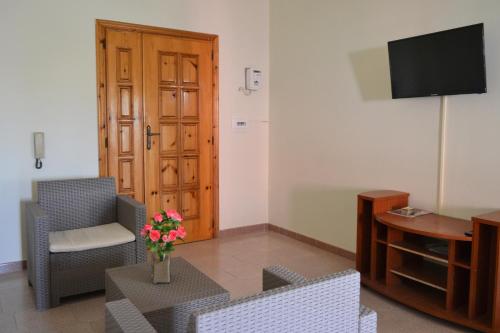 a living room with chairs and a tv and a table at Appartamenti e Stanze Onde Blu in Le Castella