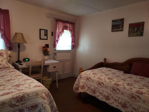 a bedroom with two beds and a desk and a window at Serenity Motel in Shaftsbury