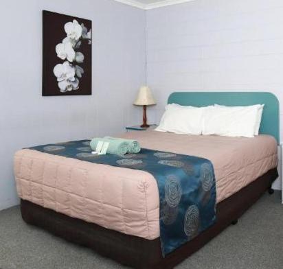 a bedroom with a large bed with a blue headboard at Albatross Motor Inn in Lakes Entrance