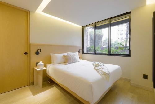 a bedroom with a white bed and a window at Capitalia Aristoteles Polanco in Mexico City