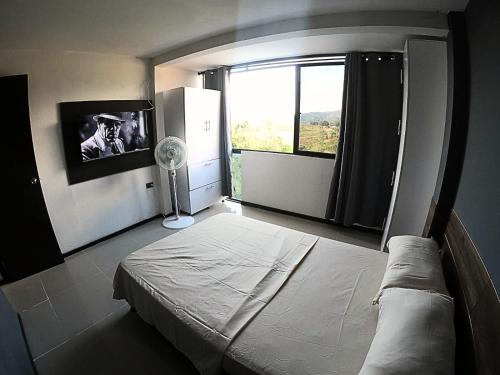 1 dormitorio con cama y ventana grande en Apartaestudio en combia cerca aeropuerto PEI, en Pereira