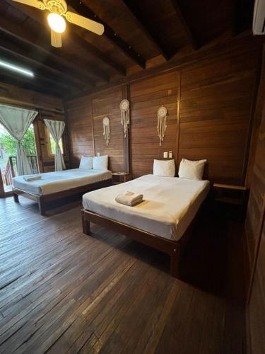 two beds in a room with wooden walls and wooden floors at Lura Bacalar in Bacalar