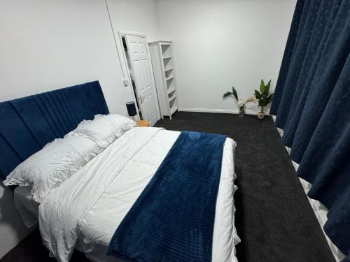 Schlafzimmer mit einem großen Bett und blauen Vorhängen in der Unterkunft Cheam Apartment in Cheam