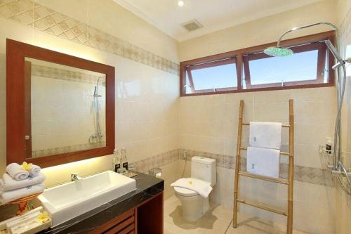 a bathroom with a sink toilet and a mirror at Kubu GWK Villa in Jimbaran