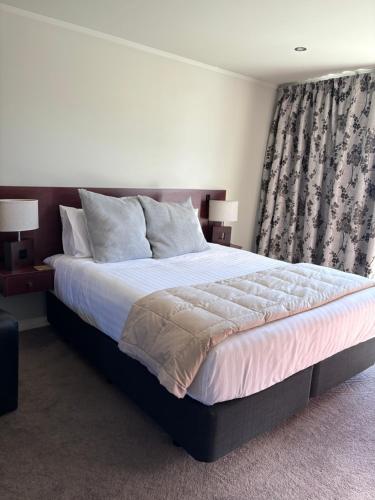 a bedroom with a large bed and a window at Village Apartments Gisborne in Gisborne